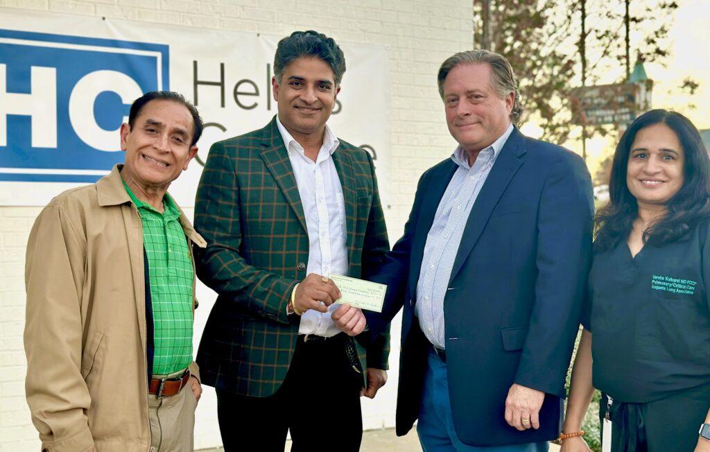 Dr. Sanjeev Kapuria, Dr. Vishal Sharma, James Stiff, and Dr. Varsha Kulkarni stand together, presenting a $3,500 donation check for hurricane recovery efforts.